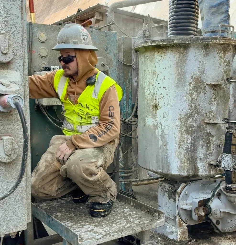 Operator standing on platform monitoring automated grouting equipment.