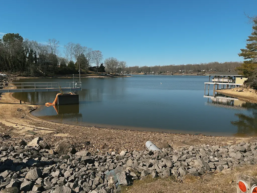 Grout-mixer-dam-project - Pennsylvania Drilling Company An open lake with a pier, rocks, and trees surrounding it