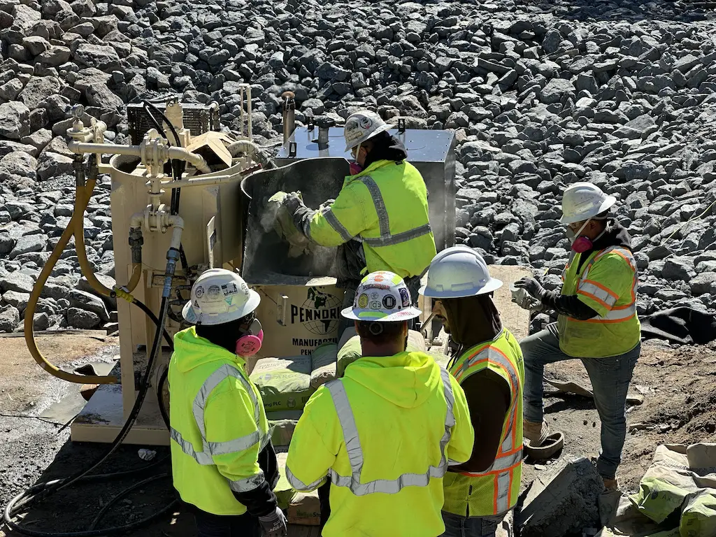 PD411H-Grout-Mixer - Pennsylvania Drilling Company 5 construction workers in PPE standing around a grout mixer operating the PD411H